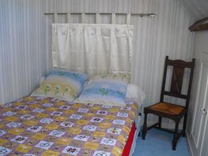 a bedroom with a bed with a window and a chair at Vacances à Réthoville in Réthôville