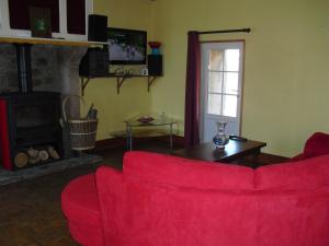 a living room with a red couch and a fireplace at Vacances à Réthoville in Réthôville