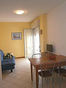 un soggiorno con tavolo, sedie e televisione di De La Mariute a Bibione