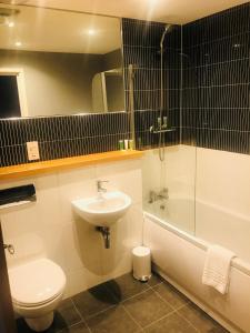 a bathroom with a sink and a toilet and a tub at Ice House Apartments in Swansea +39 photos