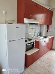 cocina con armarios rojos y nevera blanca en Nefeli Apartments, en Stoupa