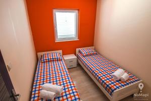 two beds in a small room with orange walls at Apartment M&M in Sveti Stefan