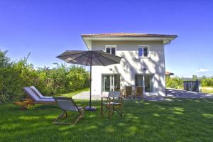 un patio con sillas y una sombrilla frente a una casa en villa Evian Neuvecelle, en Neuvecelle