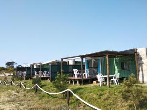 a house with chairs and tables in front of it at La Isla in Punta Del Diablo