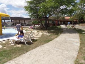 a woman sitting in a chair next to a pool at Flat Fazenda Cond Monte Castelo-Ao lado da Piscina in Gravatá