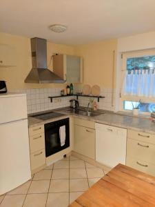 a kitchen with white cabinets and a stove top oven at FeWo Am Ohrensbächle in Glottertal