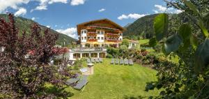 duży budynek na trawniku z górami w tle w obiekcie Landhaus Pfurtscheller w Neustift im Stubaital