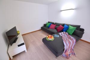 a living room with a black couch with colorful pillows at Casa da Baía - Guest House in Horta
