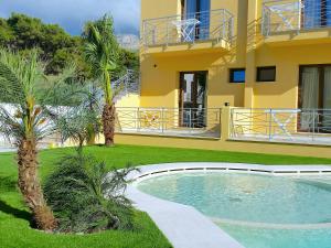 a yellow house with a swimming pool and palm trees at Residence Le Piscine in San Vito lo Capo