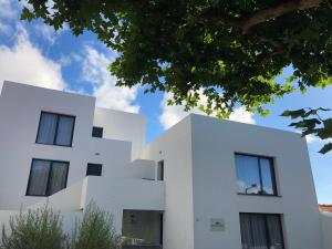 una casa blanca con ventanas negras y un árbol en Apartamentos Basalto, en Madalena