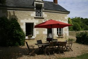 a table and chairs with a red umbrella in front of a building at Gîte du Moulin de Montrésor in Montrésor