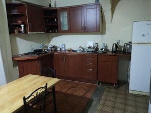 a kitchen with wooden cabinets and a table and a refrigerator at Albatross Kvariati Guest House in Kvariati +50 photos