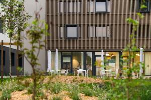 een gebouw met tafels en stoelen ervoor bij Hotel Enight in Gradignan