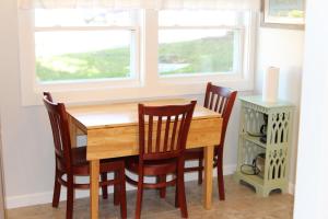 a dining room table with four chairs and two windows at Elmwood Motor Court in Old Orchard Beach