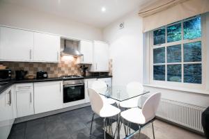 une cuisine avec des placards blancs et une table et des chaises en verre dans l'établissement Apartment 2 The Grove, à Durham