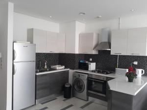cocina con armarios blancos, lavadora y secadora en Harmony Appartement 12 en Túnez