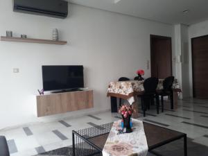 sala de estar con TV, mesa y sillas en Harmony Appartement 12 en Túnez