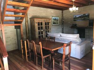 a dining room with a table and chairs and a couch at Chalé da Bel in Santo Antônio do Pinhal
