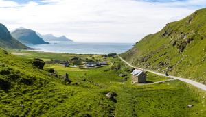 a road in the mountains with the ocean in the background at Feriehus med flott havutsikt ved Hauklandstranden in Leknes