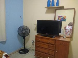 a woman standing in a mirror next to a television on a dresser at Hospedagem Vovó Gina in Aracaju