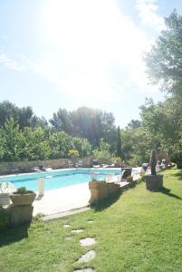 una piscina en un patio con sillas y árboles en Le Mas des Chênes, en Rognes