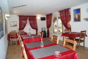 a dining room with red clothed tables and chairs at Le Mas des Chênes in Rognes