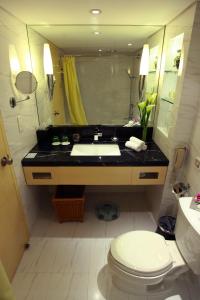 uma casa de banho com um lavatório, um WC e um espelho. em Jin Jiang Tower em Xangai