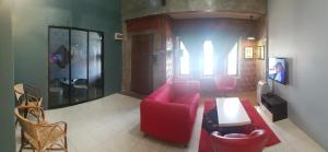 uma sala de estar com um sofá vermelho e cadeiras em Andak Home2stay em Ipoh