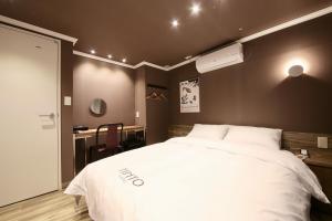 a bedroom with a large white bed and a desk at Tinto Hotel in Busan