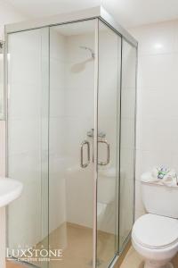 拉巴斯的住宿－Luxstone Executive & Suites，一间带卫生间的浴室内的玻璃淋浴间