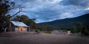 a small building with a mountain in the background at Grampians Pioneer Cottages in Halls Gap