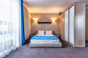 Schlafzimmer mit einem Bett mit blauer Bettwäsche und weißen Kissen in der Unterkunft AYKUN Hotel by AG Hotels Group in Astana