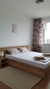 een slaapkamer met een groot houten bed en een raam bij GENIKO Apartments in Pomorie