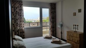 a bedroom with a bed and a window with a balcony at GENIKO Apartments in Pomorie