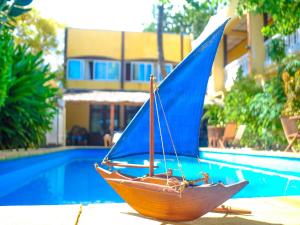 um barco de brinquedo de madeira com uma vela azul ao lado de uma piscina em Hôtel Restaurant Coco Lodge Majunga em Mahajanga