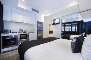 a hotel room with two beds and a kitchen at Silkari Suites at Chatswood in Sydney