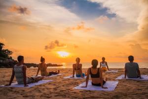 eine Gruppe von Leuten, die am Strand sitzen und Yoga machen in der Unterkunft CC's Hideaway Kata - SHA Plus in Kata Beach