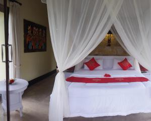a bedroom with a white bed with red pillows at Toyabali Resort, Dive & Relax in Tulamben