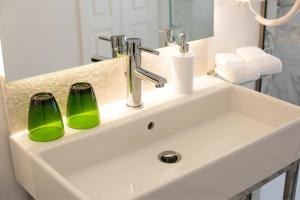 ein Waschbecken mit zwei grünen Gläsern darauf in der Unterkunft Theotoki Liston Suite in Korfu-Stadt