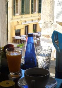 einen Tisch mit zwei Gläsern und einer blauen Flasche darauf. in der Unterkunft Theotoki Liston Suite in Korfu-Stadt
