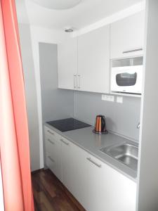 een witte keuken met een wastafel en een magnetron bij apartmán Oblík - penzion Kilián in Kvilda