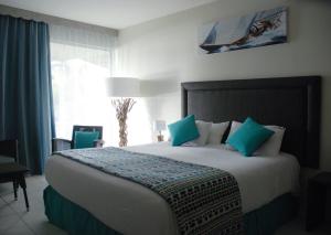 a bedroom with a large bed with blue pillows at Hotel Fleur d'Epee - Plage de Bas du Fort in Le Gosier