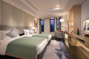 a hotel room with two beds and a desk at Somerset Harmony City Wuxi in Wuxi