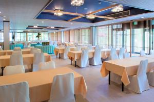 un salón de banquetes con mesas y sillas blancas en Takamiya Hotel Jurin en Zao Onsen