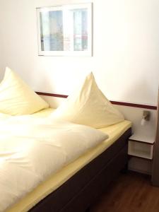 1 cama con sábanas blancas y almohadas en una habitación en Hotel Adler, en Babenhausen