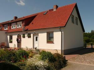 une maison avec un toit rouge et une personne debout devant elle dans l'établissement FeWo Karnitz/Rügen, à Karnitz