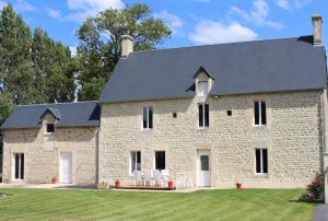 a large stone house with chairs in the yard at La ferme de Fumichon in Tour-en-Bessin