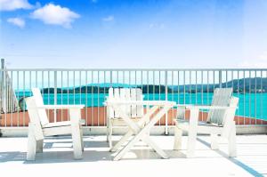 two chairs and a table on a deck with the water at Guest House Amakara Okinawa in Nago