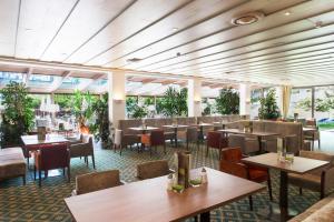 a restaurant with tables and chairs and windows at Hotel Alpenhof in Sankt Jakob in Defereggen