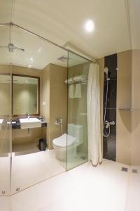 a bathroom with a glass shower and a toilet and a sink at Great Diponegoro Hotel Surabaya in Surabaya